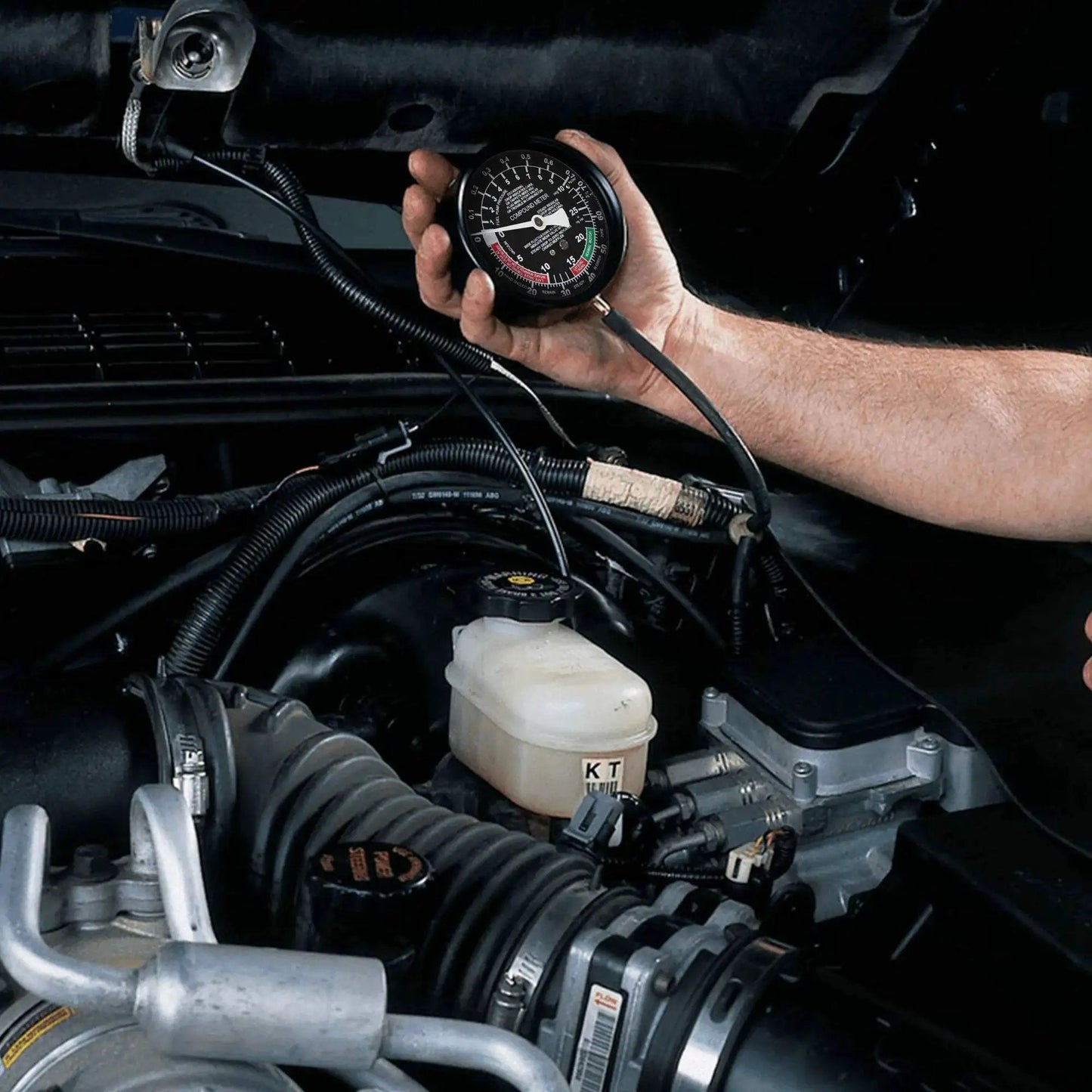 Hand holding Fuel Pump And Vacuum Carburetor Pressure Tester Gauge Kit For Engine Diagnostics under vehicle hood