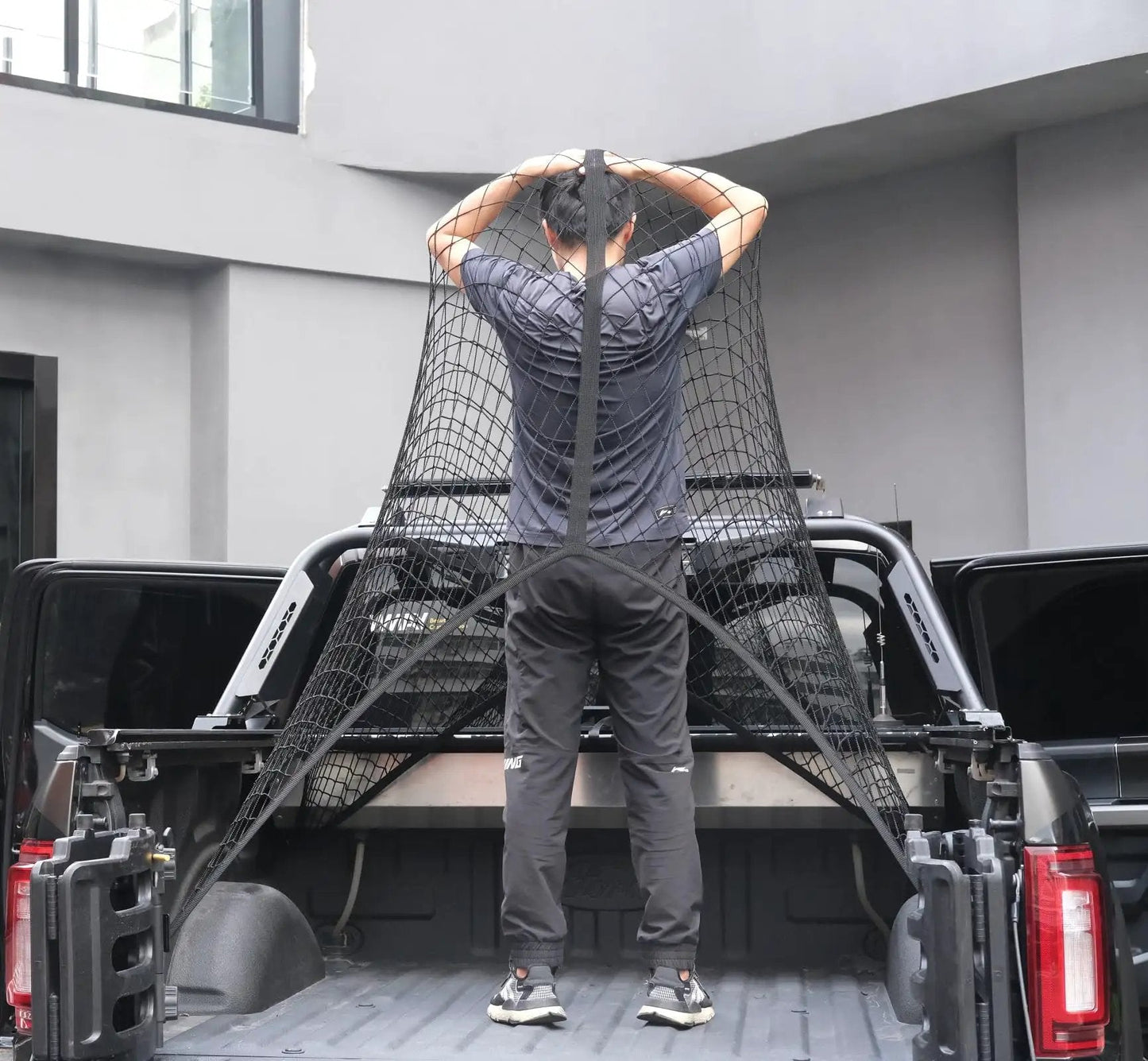 Person installing an elastic cargo net for truck bed and SUV to secure lightweight loads in place.