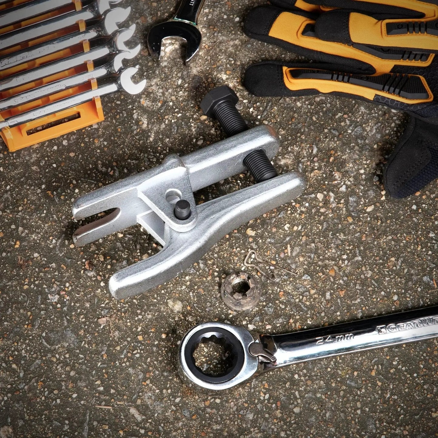 Adjustable Ball Joint Separator for Front Wheel Drive Cars and Light Trucks with tools on a concrete surface.