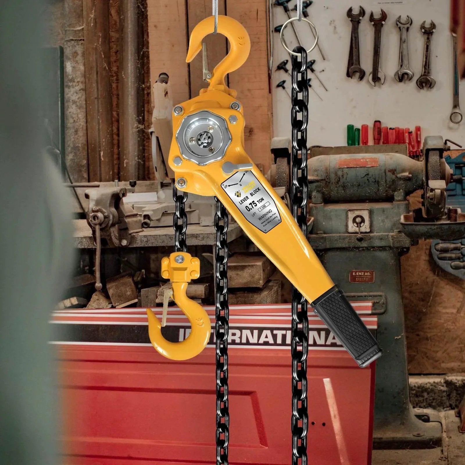0.75 Ton Manual Lever Chain Hoist with G80 galvanized carbon steel construction, yellow handle, hanging in a workshop.