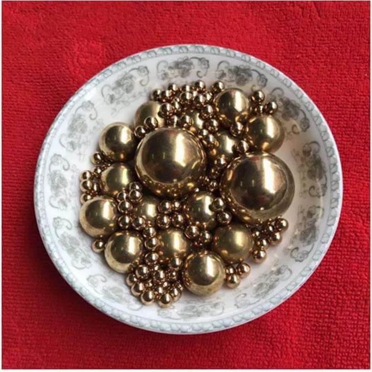 12mm 50pcs Solid Pure Copper Balls - Brass Ball Bead displayed in a decorative dish on a red background