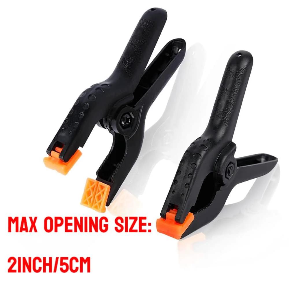 Two 2-inch heavy duty plastic spring clamps with orange tips, ideal for crafts and photography use, showcasing comfort grip design.