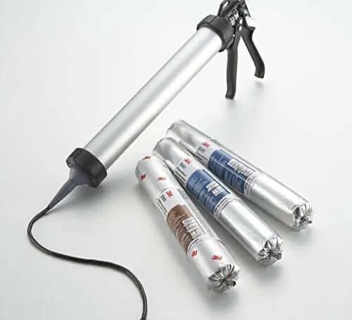Large caulking gun with polyurethane adhesive tubes for glass, automotive, construction; tubes labeled in metallic wrap.