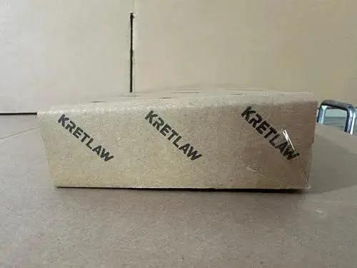 Side view of cardboard box labeled KRETLAW, showcasing packaging for Mini Grease Gun Kit 3000 PSI With Double 3oz Cartridges And 12 Inch Flex Hose Pro Grade Reinforced Coupler For Automotive And Marine Use Includes Extension Pipe 4 Jaw Coupler Sharp Nozzle Extension Adapter And Gloves.