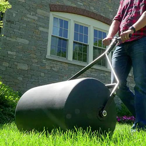 Person using Powerful 270 Lb Poly Lawn Roller For Push Or Tow With Easy Turn Tethered Plug And Quick Filling Drum 18 By 24 Inches