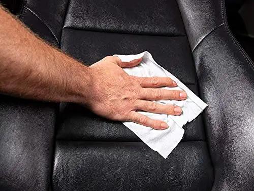 Person using Gold Class Leather Wipes For Cars All In One Leather Cleaner Conditioner And Protector With Aloe Moisturizers on a car seat.