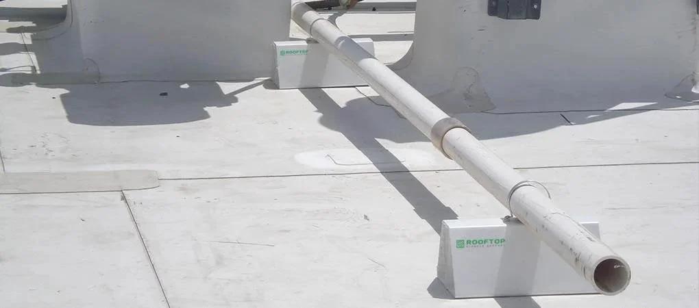 4 Pack 6 Inch Pre Cut PVC Rooftop Pipe Support Blocks For Roof Conduits And Piping On Roofs Versatile Heavy Duty Cost Effective PVC Blocks For Small Water Gas Electrical Metal Plumbing Condensate And Refrigeration Lines installed on a flat rooftop supporting conduit.