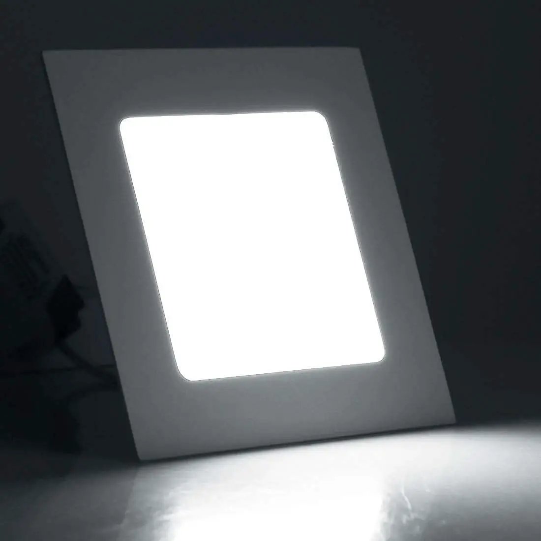 Square LED panel light emitting bright white light against a dark background