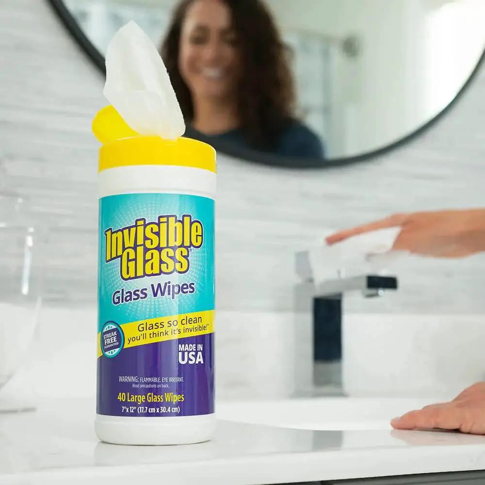 Pack Of 3 Pre-Moistened Glass Wipes, Streak-Free And Lint-Free For Windows, shown beside a smiling person in a bathroom.