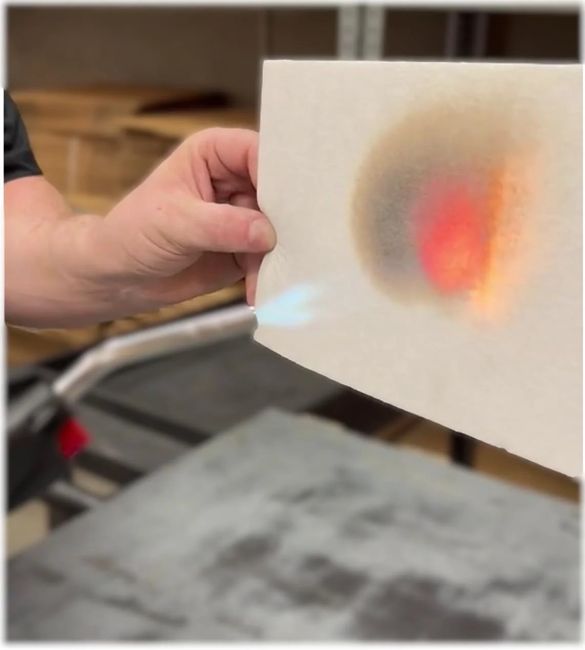 Person holding Ceramic Fiber Paper For Kilns And Furnaces 1/8 Inch Thick 11 By 12 Inch Pack Of 10 Sheets with flame applied