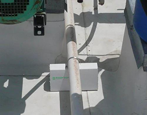 Installed 4 Pack 6 Inch Pre Cut PVC Rooftop Pipe Support Blocks for Roof Piping under a pipe on a flat roof.