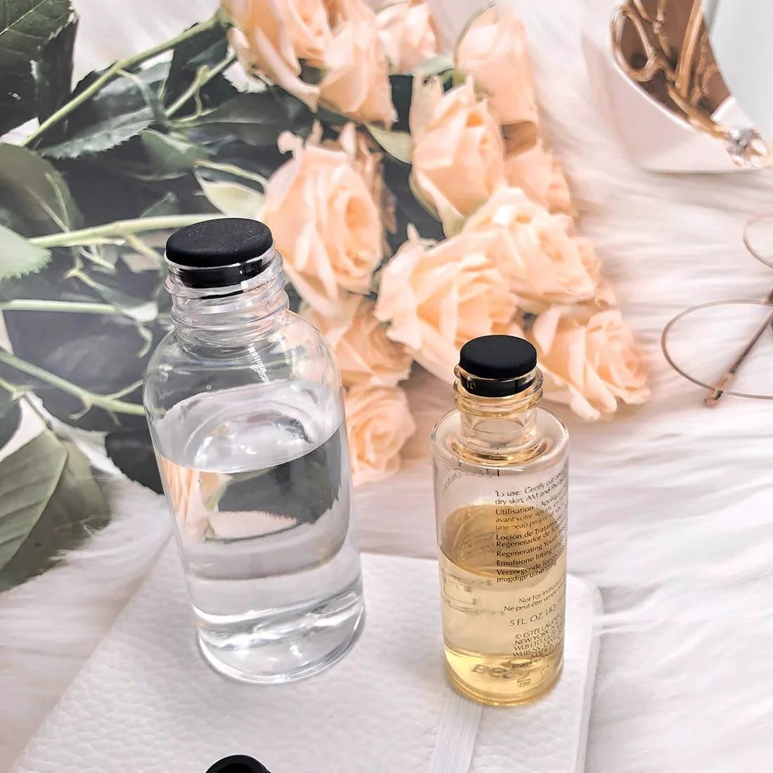 Glass bottles with liquid on a table with roses, featuring black caps, related to 80 Pieces Silicone Hole Plugs Kit With 7 Sizes.