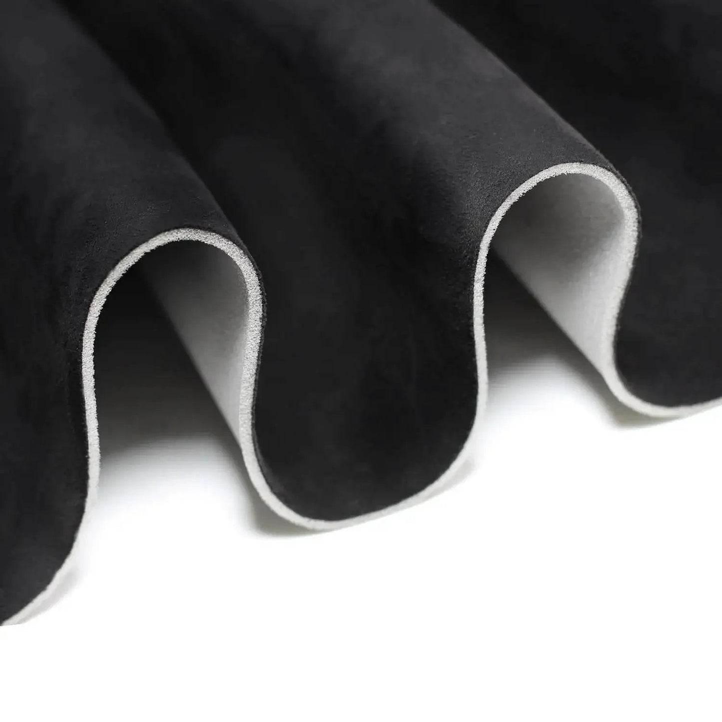 Close-up of black suede headliner fabric with foam backing for car truck SUV roof interiors, showing material texture and layers.