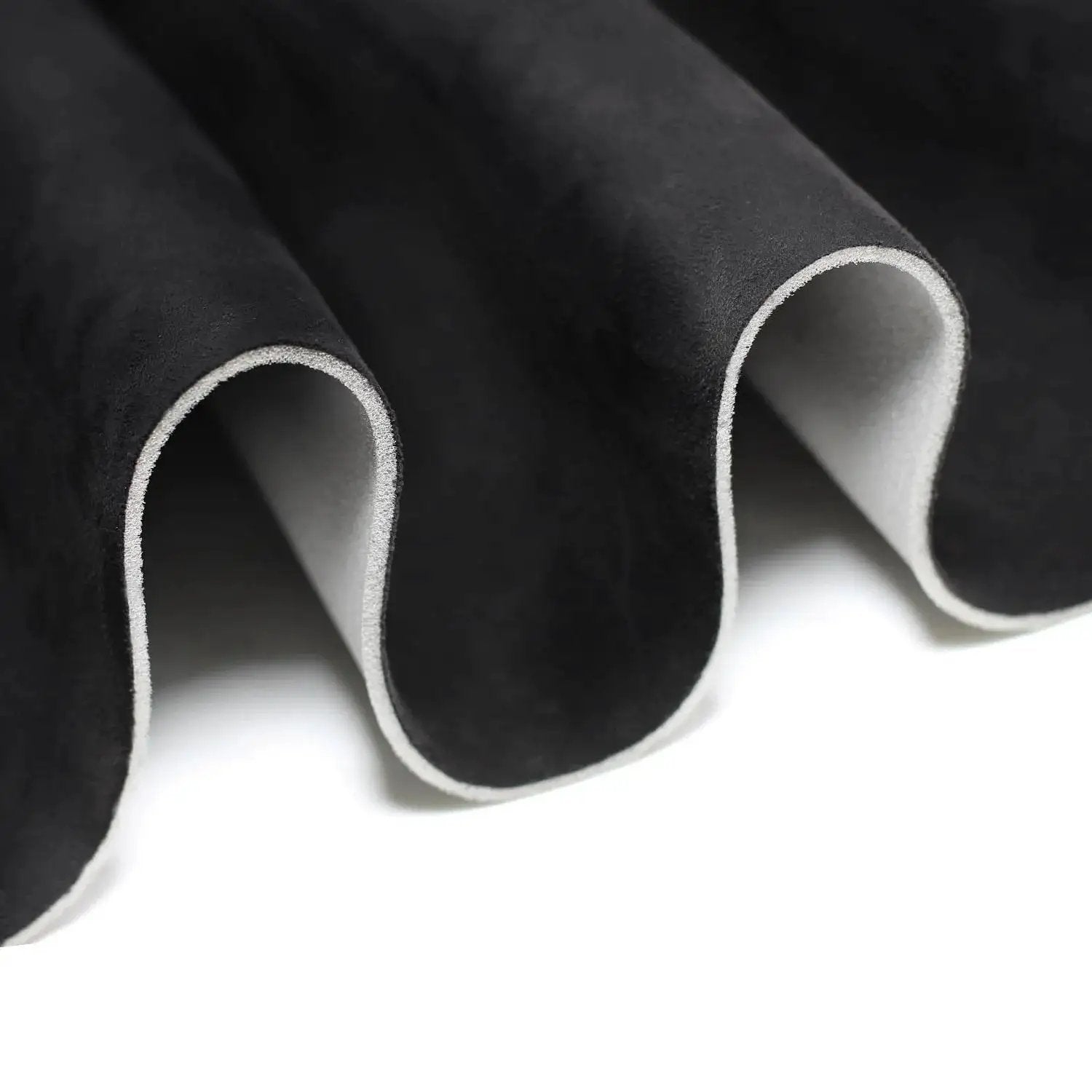 Close-up of black suede headliner fabric with foam backing for car truck SUV roof interiors, showing material texture and layers.