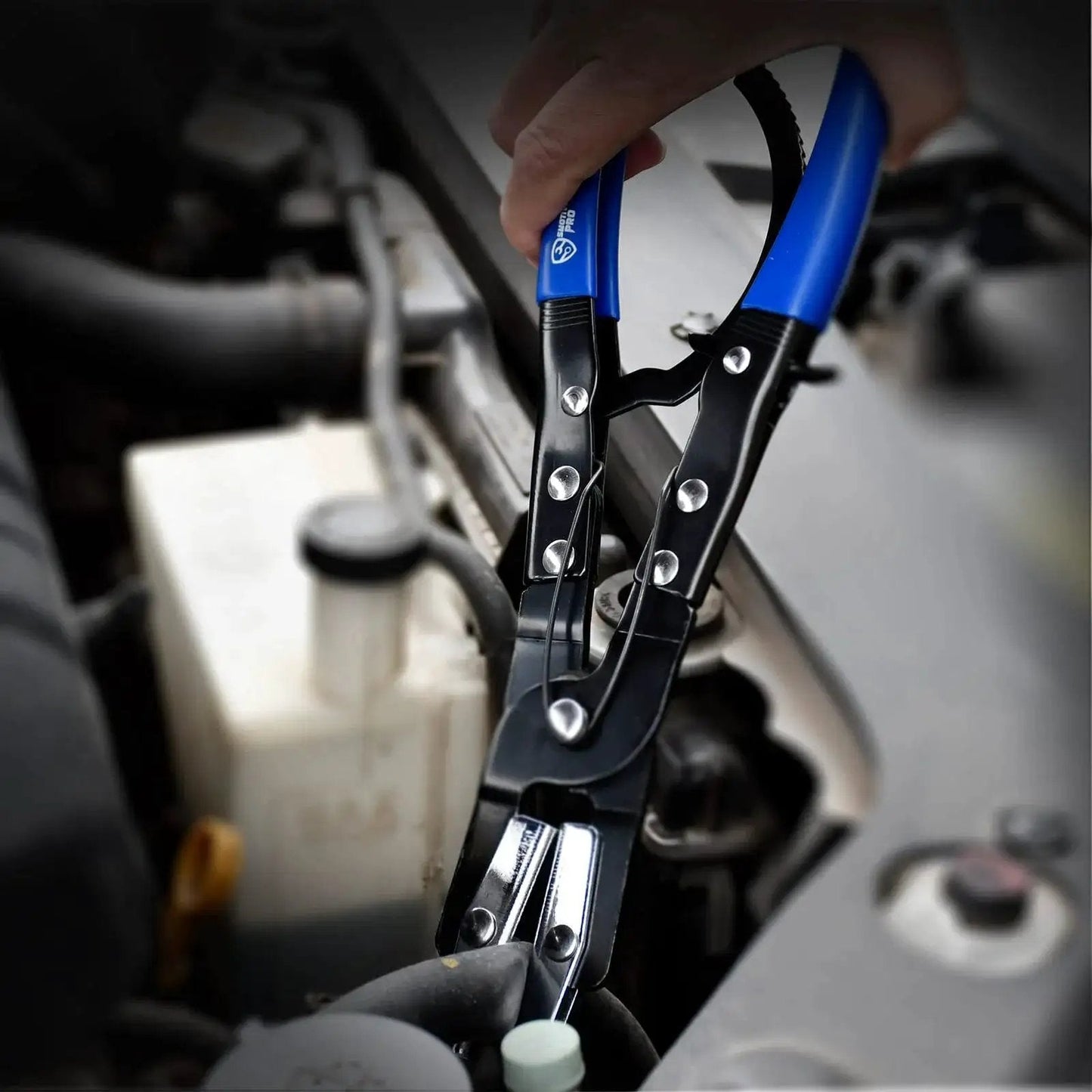 Close-up of a 3Pcs Ratcheting Hose Pinch Off Pliers Set for automotive cooling and fuel lines, blue handles, in use in car engine.
