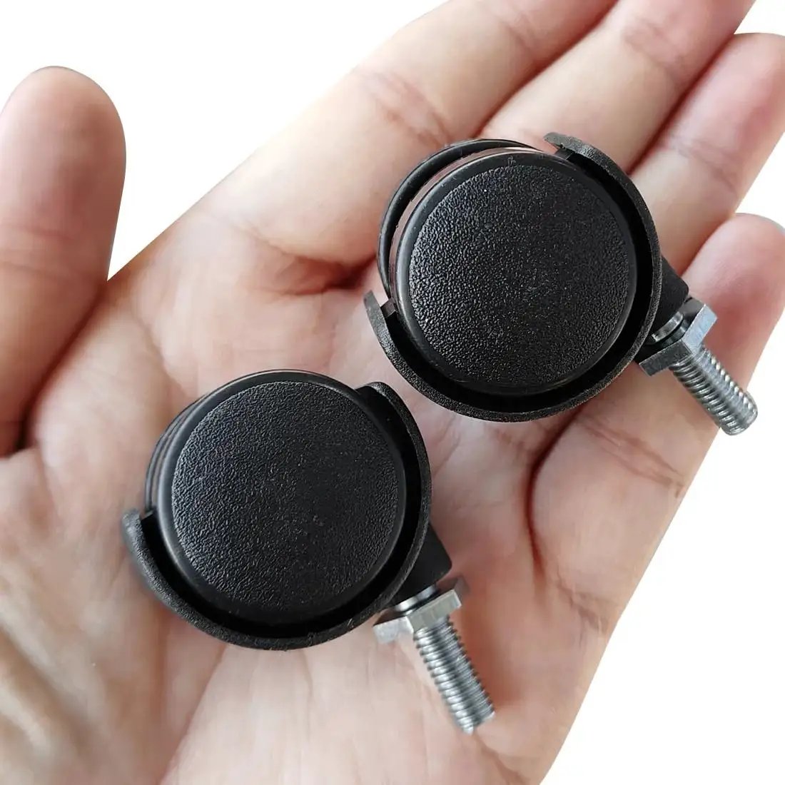Hand holding two 1.2 Inch Nylon Wheel Caster With M6 Threaded Stem Non Brake Swivel, showing black wheels and silver stems.