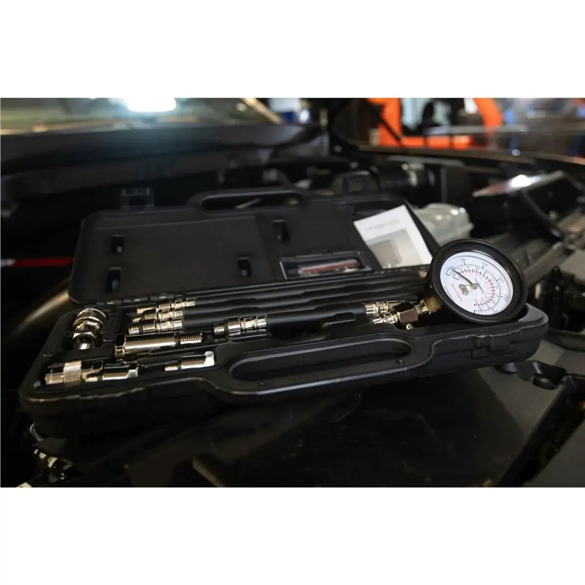 Engine Compression Test Kit With 2.75in Gauge And Quick Disconnect Adapters in open carrying case on car engine