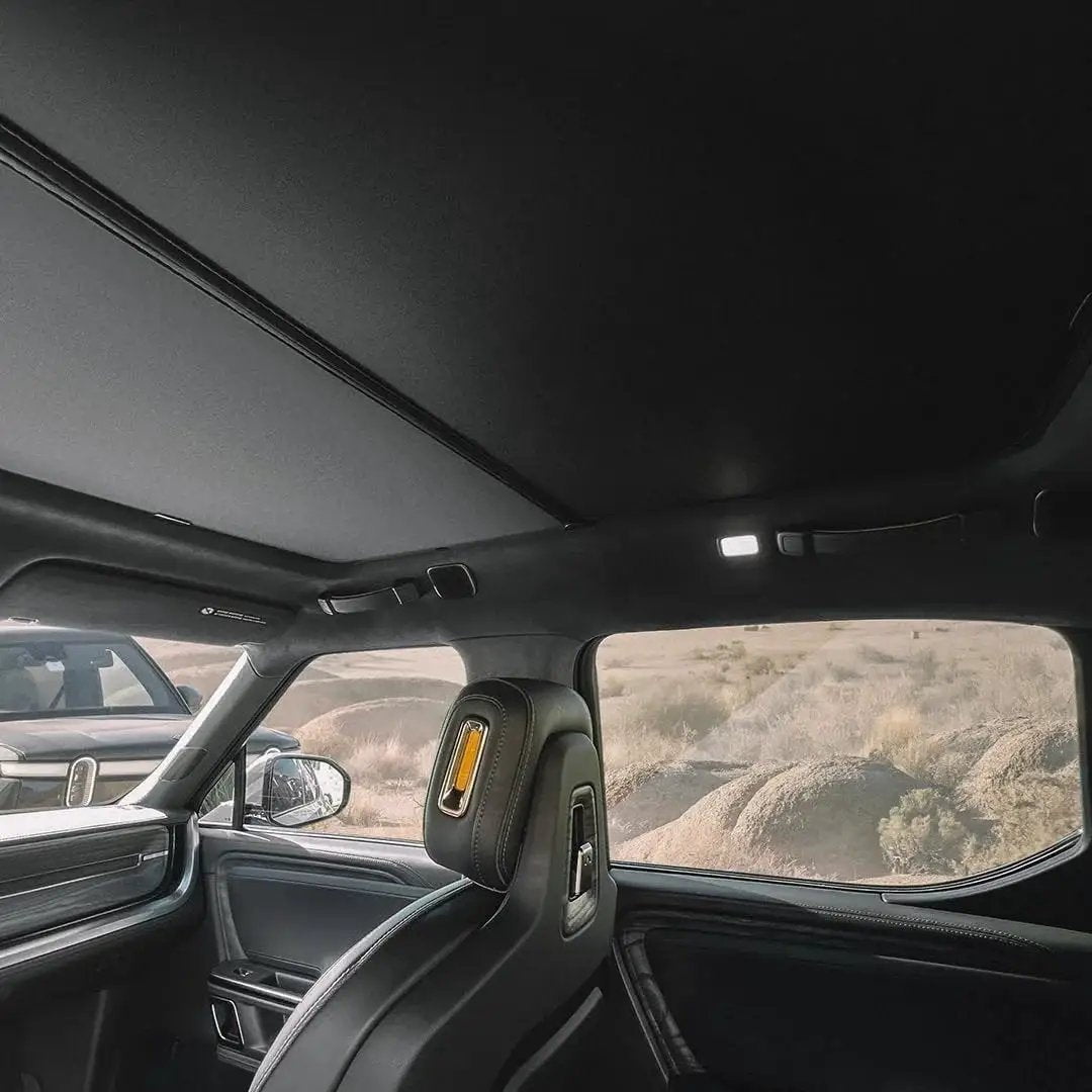 Interior view of a Rivian R1S with R1S Roof Sunshade Two Piece Full Blackout installed, blocking sunlight from roof glass.