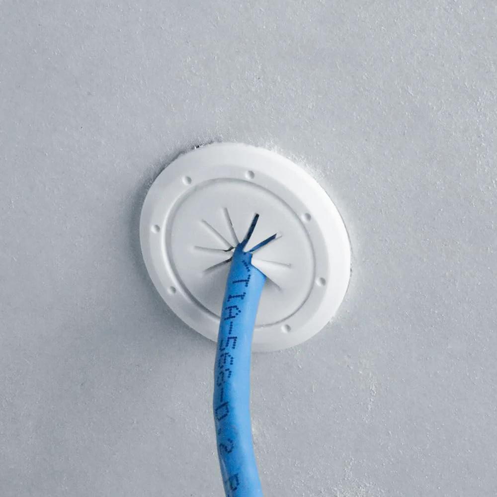 Installed Speedy Z Mini Spring-Lock Cable Pass-Through Port For Clean Wall Install In White 1.5 Inch Outer Diameter And 1 Inch Inner Diameter Ultra Low-Profile Grommet with blue cable.
