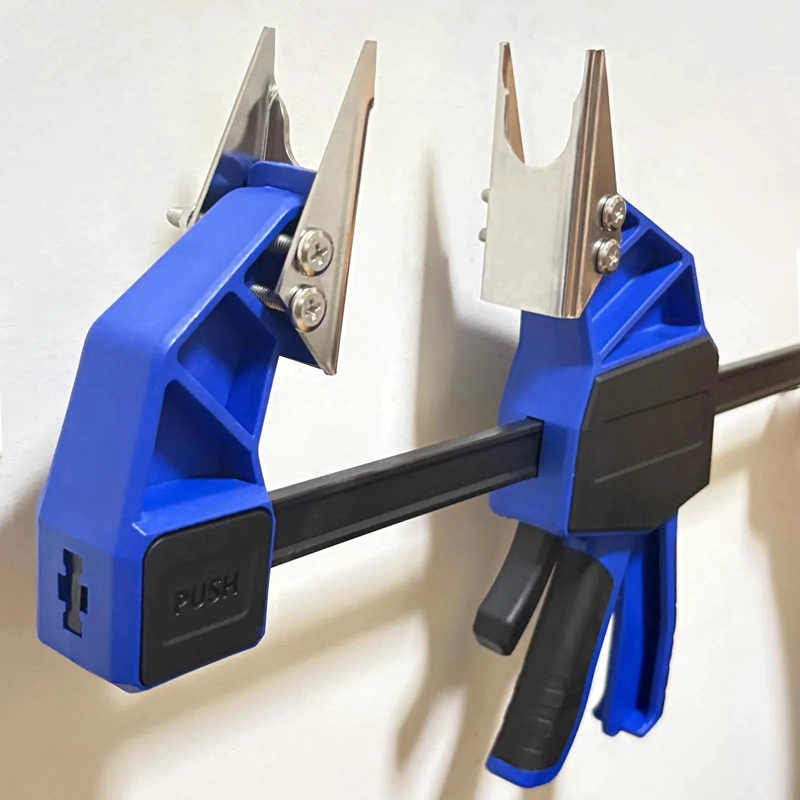 18 Inch Quick Coupler Hand Clamp Carbon Steel With Four Duo Jaw Sets Two By One Half Inch And Three Quarter Inch Two By Seven Eighths Inch And Three Eighths Inch Jaws For Hydraulic Pipe Clamps Quick Mate Coupler Tool For Excavators Tractors And Cranes, showing blue handle and silver jaws mounted on a wall.