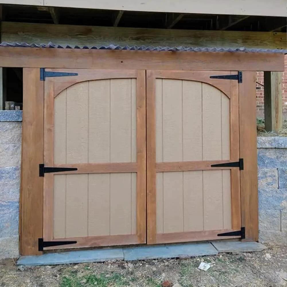 Installed wooden barn doors with black wrought iron 8 Inch T Strap Barn Door Hinges Heavy Duty Gate Hinge Set, rustproof design