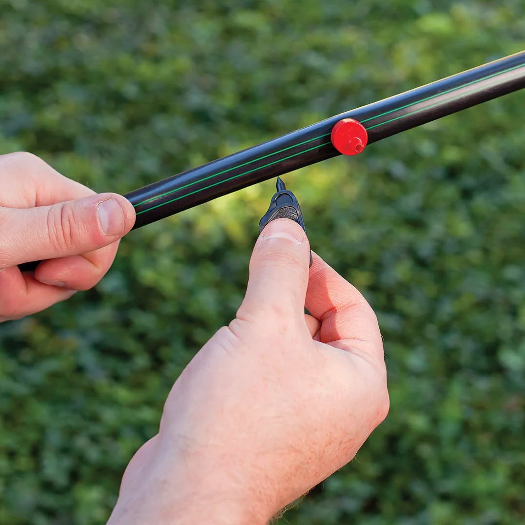 Close-up of installing heavy duty drip irrigation distribution tubing 0.634 inch outer diameter for gardens with hands.