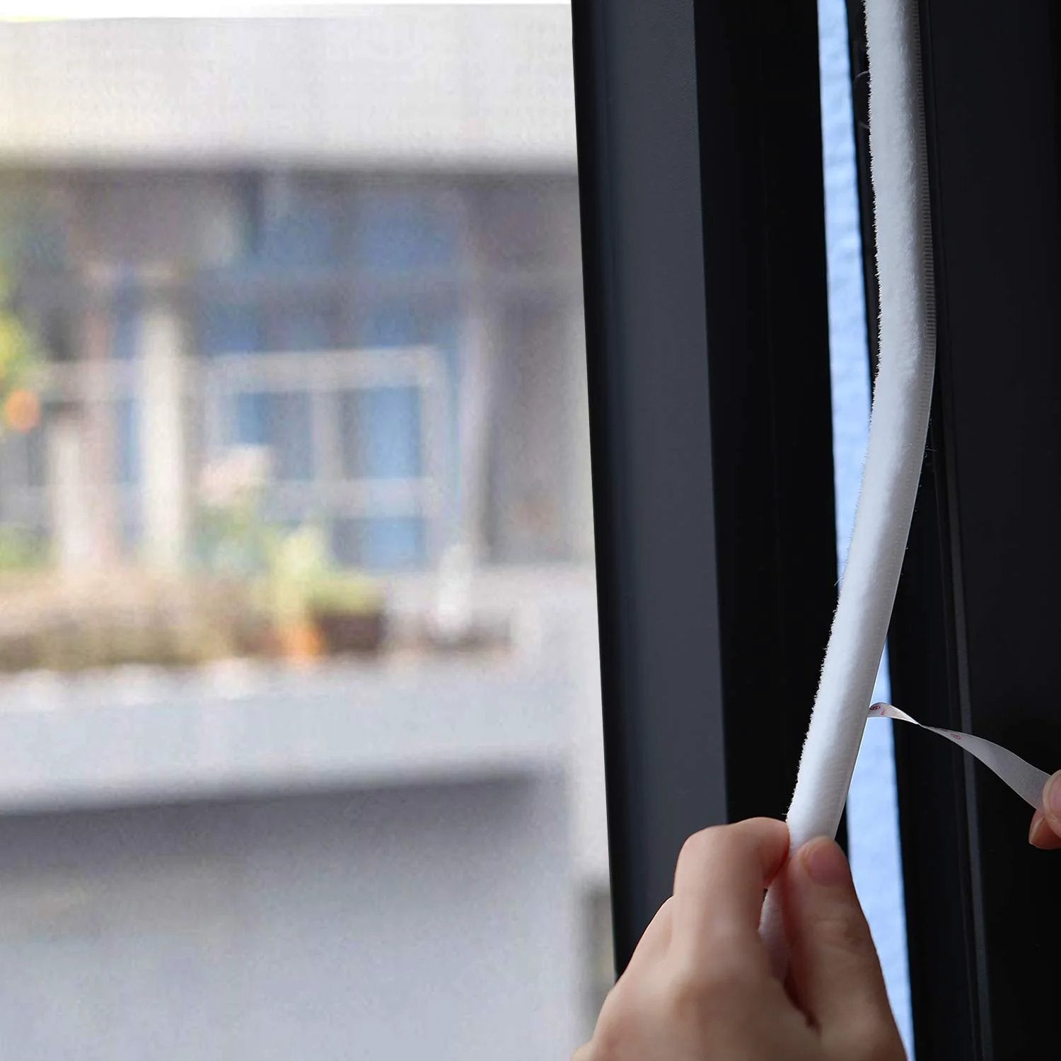 Person applying Fuzzy Brush Weatherstripping For Windows And Doors, Self Adhesive Felt Seal, 0.34375 Inch By 0.34375 Inch, 16 Ft Long