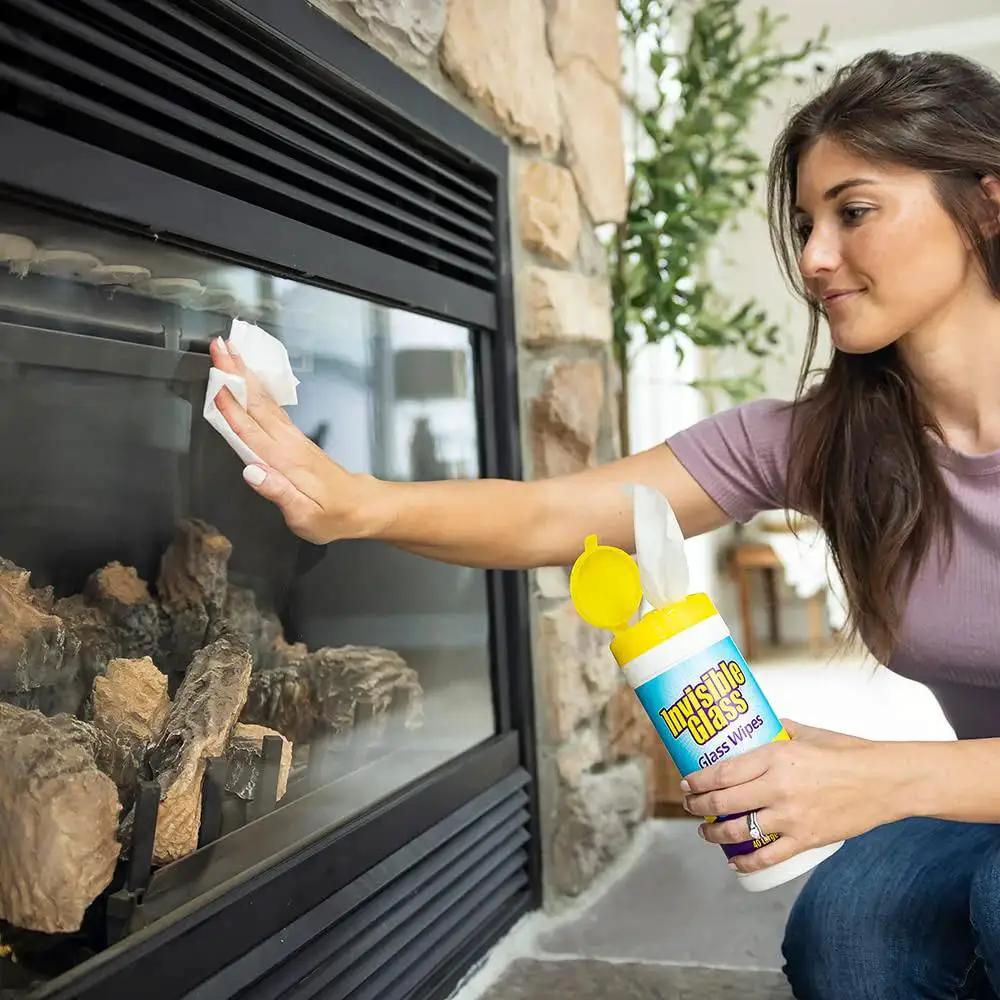 Woman using Pack Of 3 Pre-Moistened Glass Wipes, Streak-Free And Lint-Free For Windows on a fireplace glass