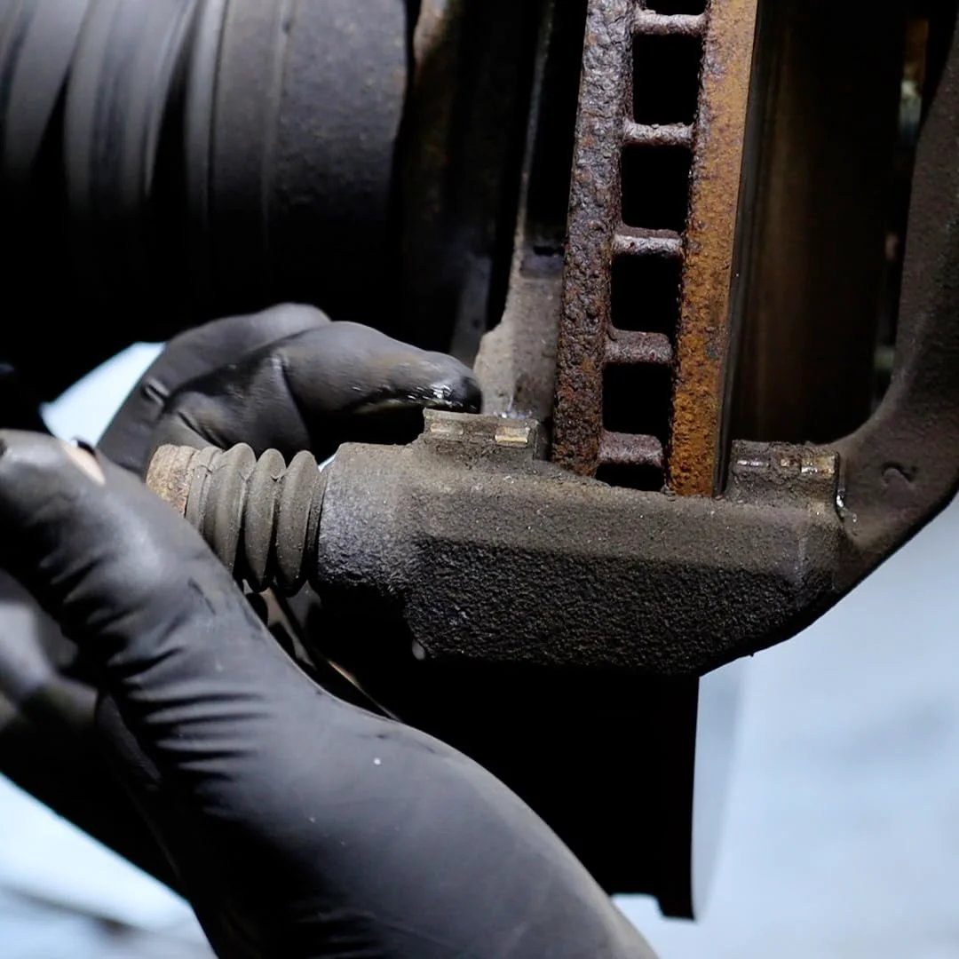 Mechanic applying Disc Brake Squeal Eliminator With Silicone Based Brake Lubricant For Full Assembly Keeps Noise Down While Shielding Components From Moisture Heat And Rust AGS Sil Glyde 4 Oz Tube to brake assembly.