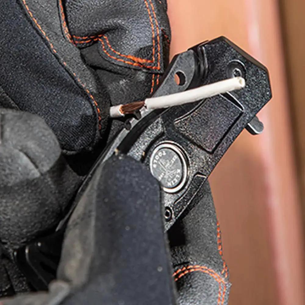 Close-up of a Folding Pocket Knife For Electricians With Bearing Assist Flipper And Frame Lock Black Handle in use with wire.