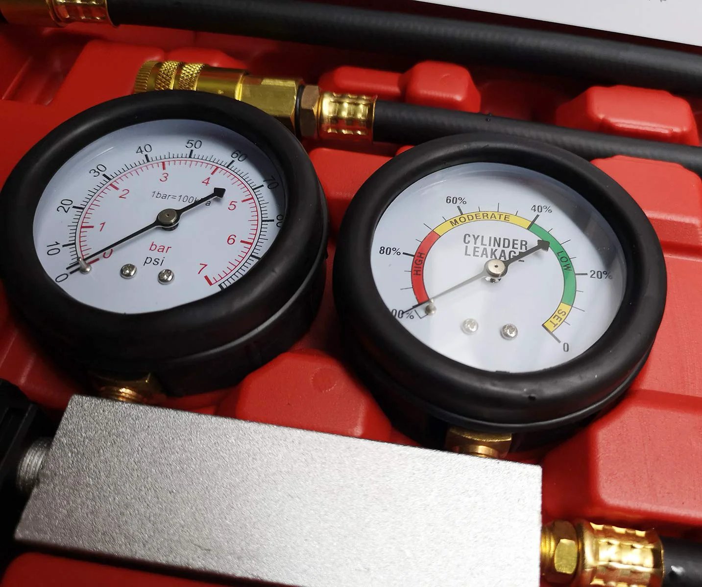 Close-up of dual gauge on Cylinder Leak Down Tester And Compression Test Kit for engine diagnostics on red background.