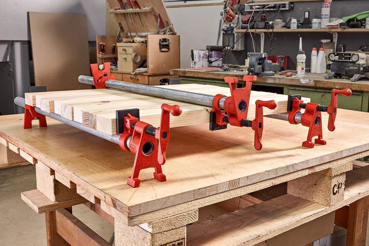 Versatile 3/4 Inch H Style Pipe Clamp For Edge Gluing And A Wide Range Of Woodworking Projects, built by Bessey, on wooden workbench.