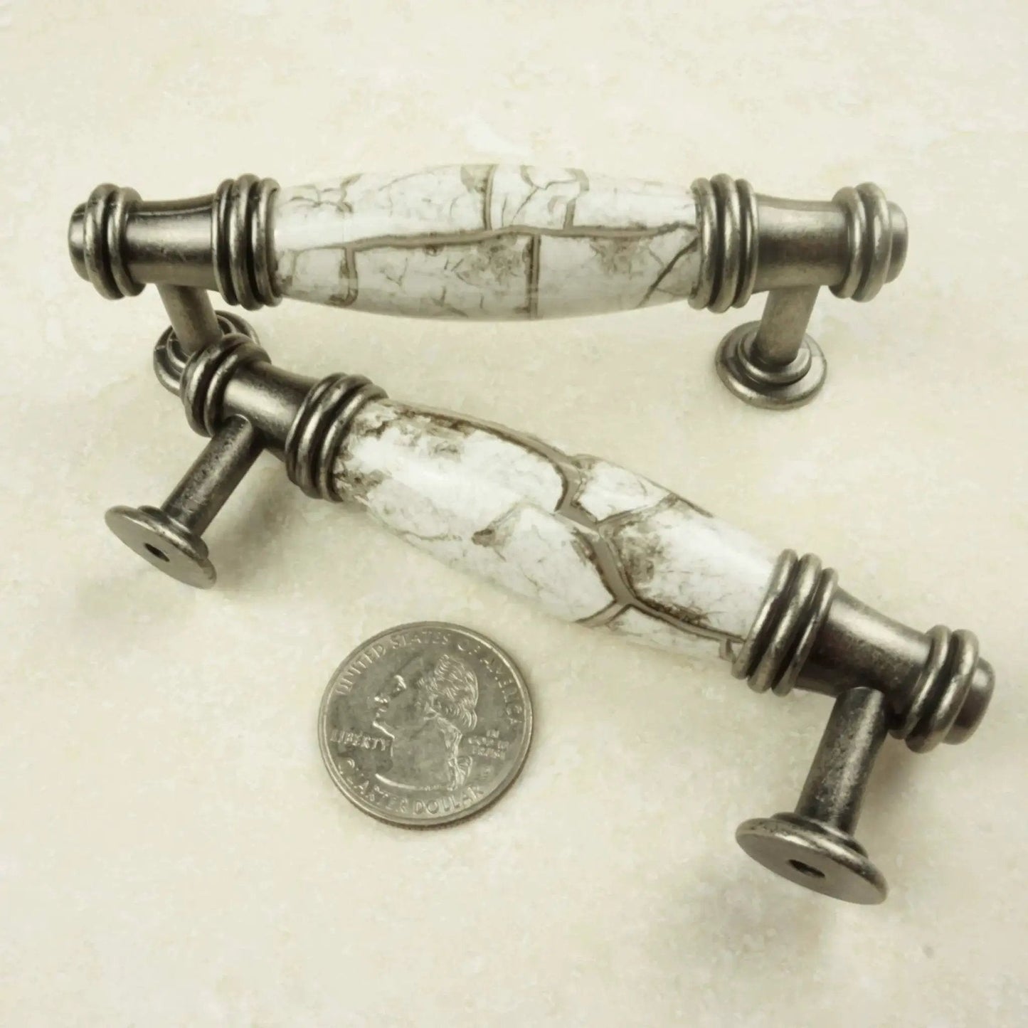 Antique silver white marble cabinet pulls with quarter for scale, detailed design.
