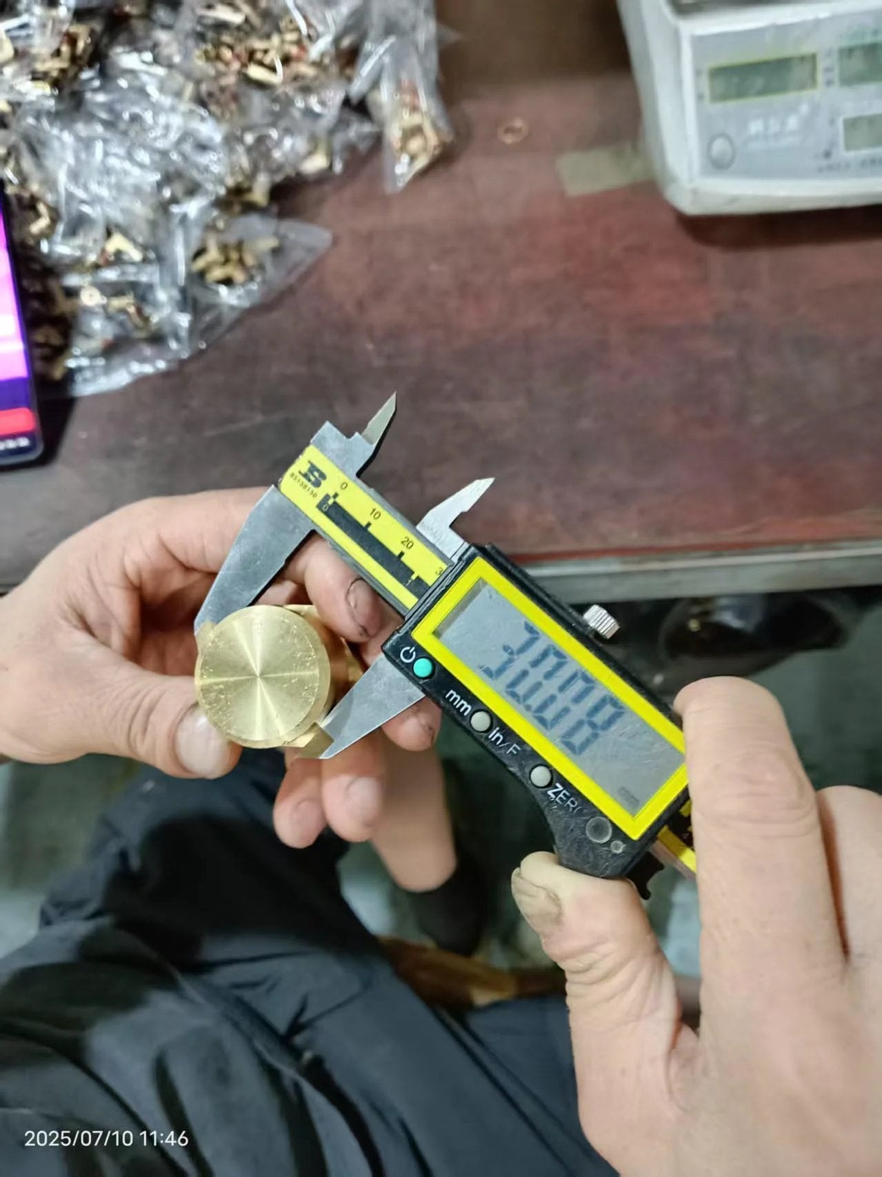 Person measuring Three Quarter Inch NPT Female Brass Pipe Cap Hex Head Fitting with caliper in workshop