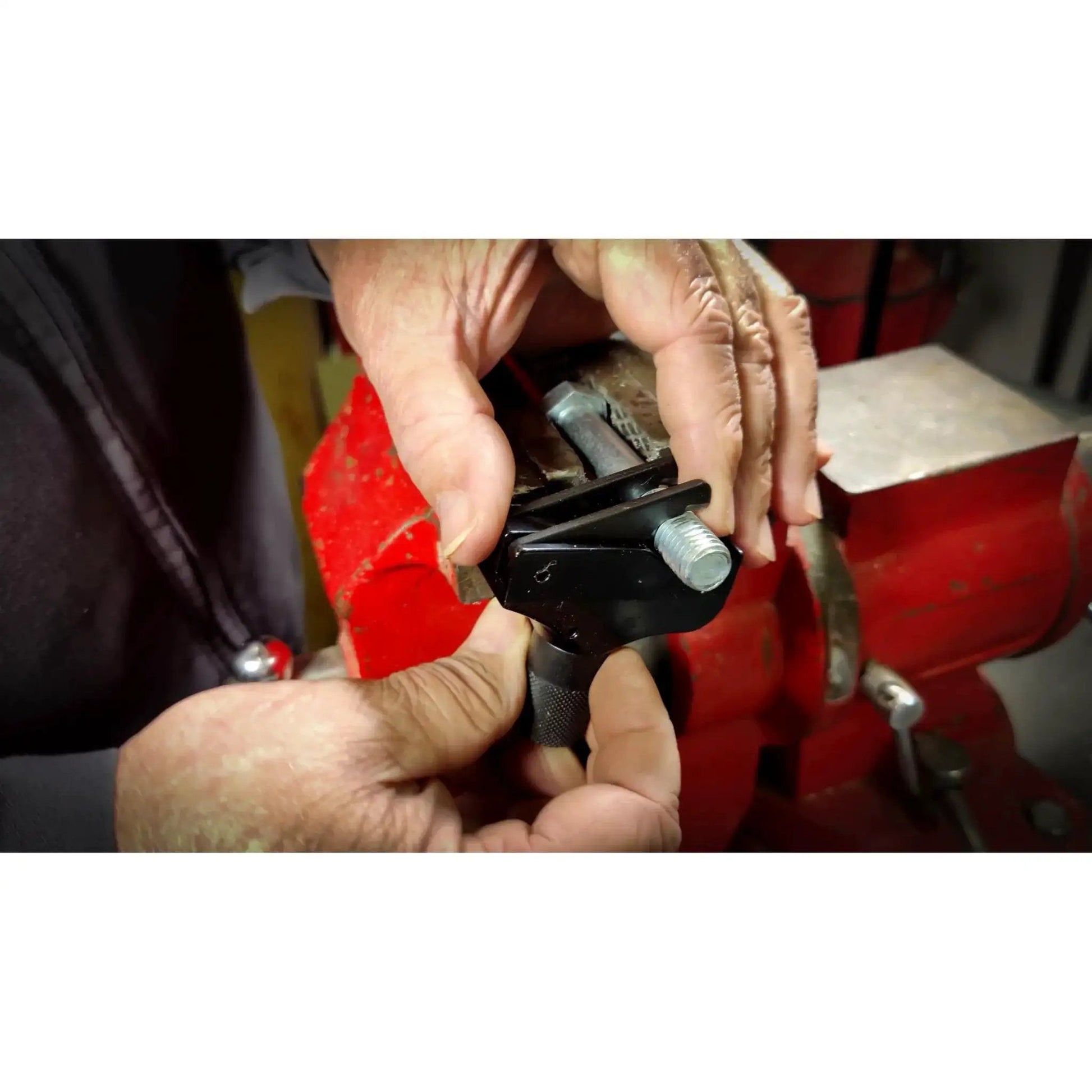 Hands using Universal Thread Repair Tool For SAE And Metric Threads With Adjustable Pitch on a metal bolt in a workshop.
