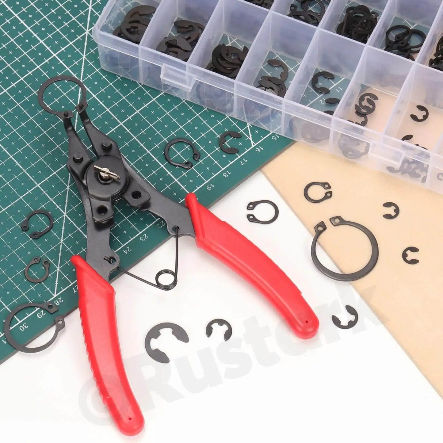All in One 4 in 1 Snap Ring Pliers Set With E Clip And C Clip Retaining Rings Kit 312 Piece Includes M1.5 To M10 E Clips And M4 To M28 C Clips Plus Tweezers For Auto DIY And Handyman Projects with red-handled pliers and assorted clips on a grid mat