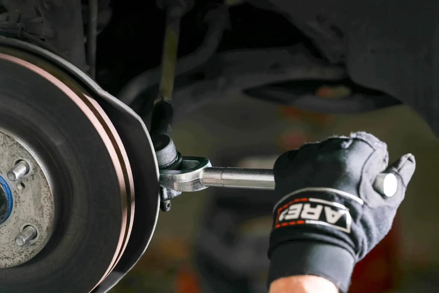 Mechanic using Ball Joint Separator Pickle Fork 15/16 Inch Tapered Fork With Knurled Handle on vehicle suspension