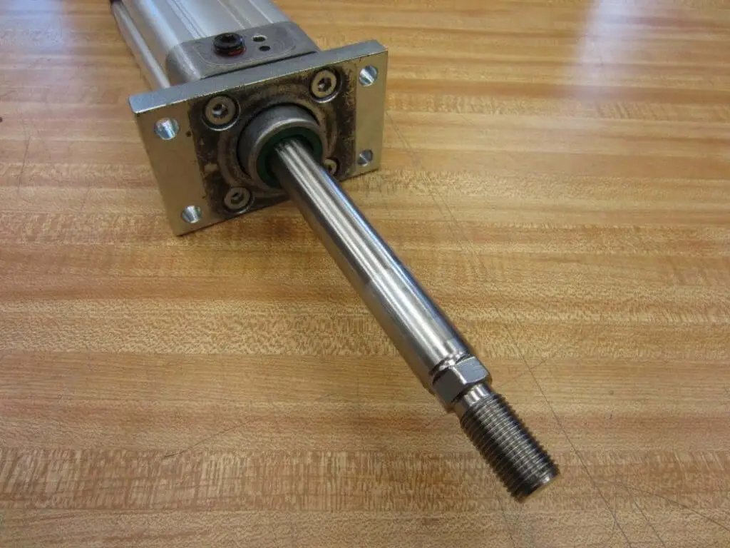 Bosch Rexroth Double Acting Cylinder 523-111-050-0 with 1/4 NPT port, close-up of 3/4 inch shaft and mounting plate on wood surface
