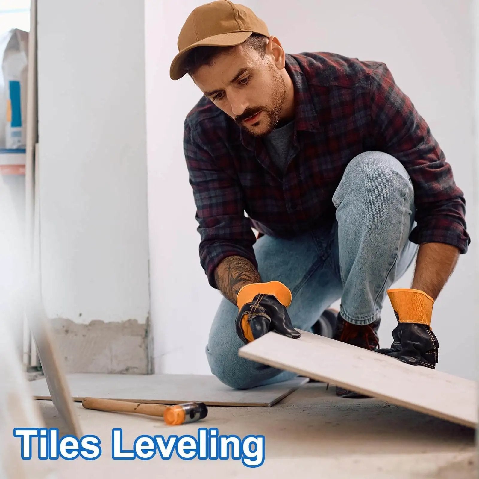 Man using plastic flat shims for leveling tiles in DIY home project, wearing gloves and cap, with hammer on floor.