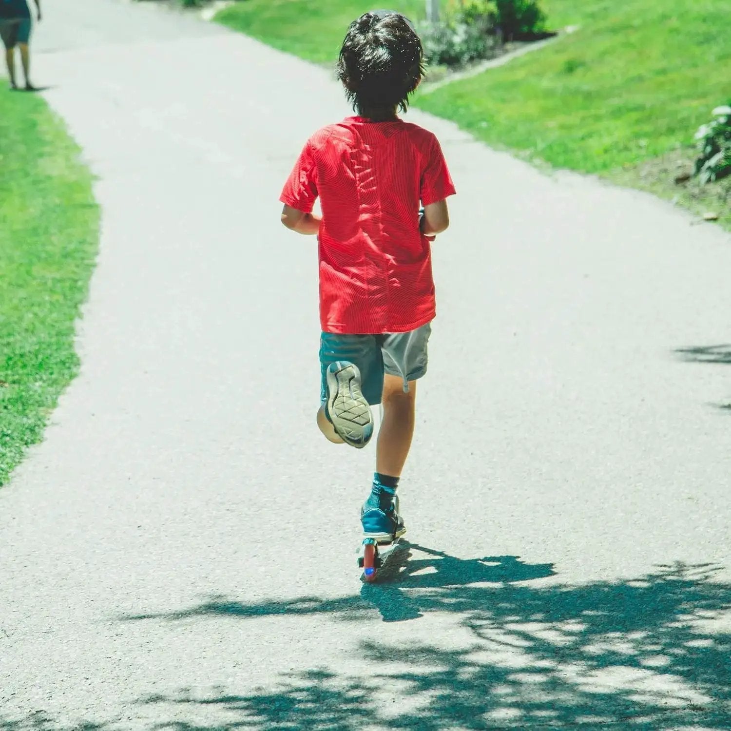Child riding a scooter on a path, showcasing High Rebound 100mm Kick Scooter Wheels With ABEC 7 Bearings for smooth rides, 4 pack.