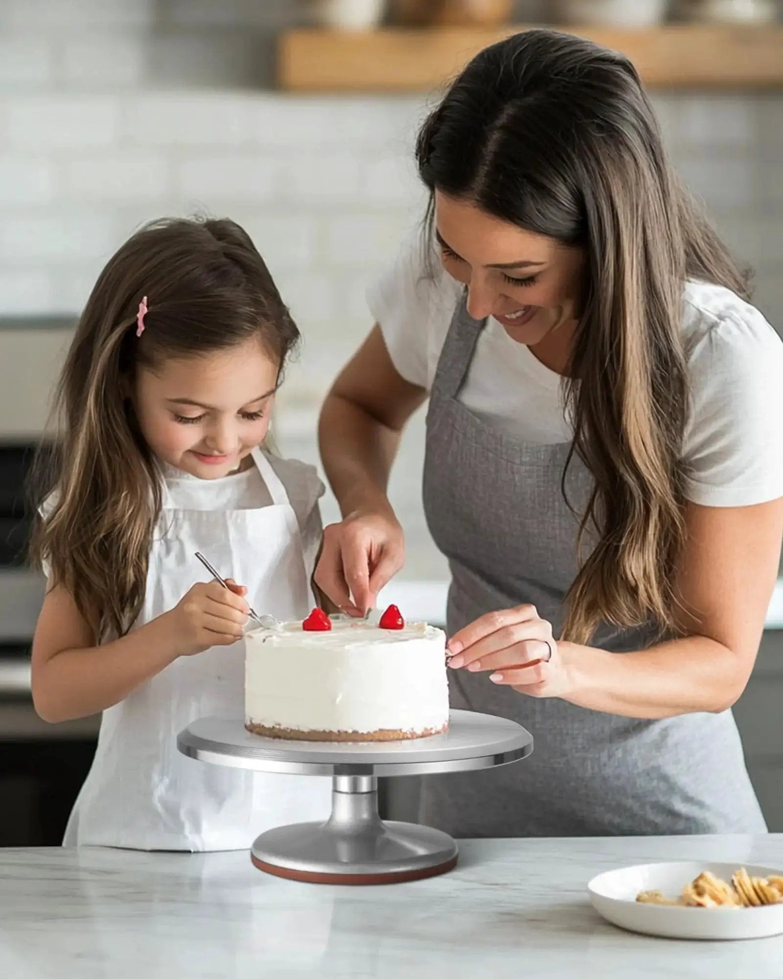 Mother and daughter decorating cake on 12 Inch Aluminum Alloy Rotating Cake Turntable With Non Slip Silicone Bottom Pro Grade Heavy Duty Revolving Cake Stand For Decorating Cakes, Pastries, And Cupcakes, Quiet Smooth Spin, Durable Kitchen Accessory For Bakers.