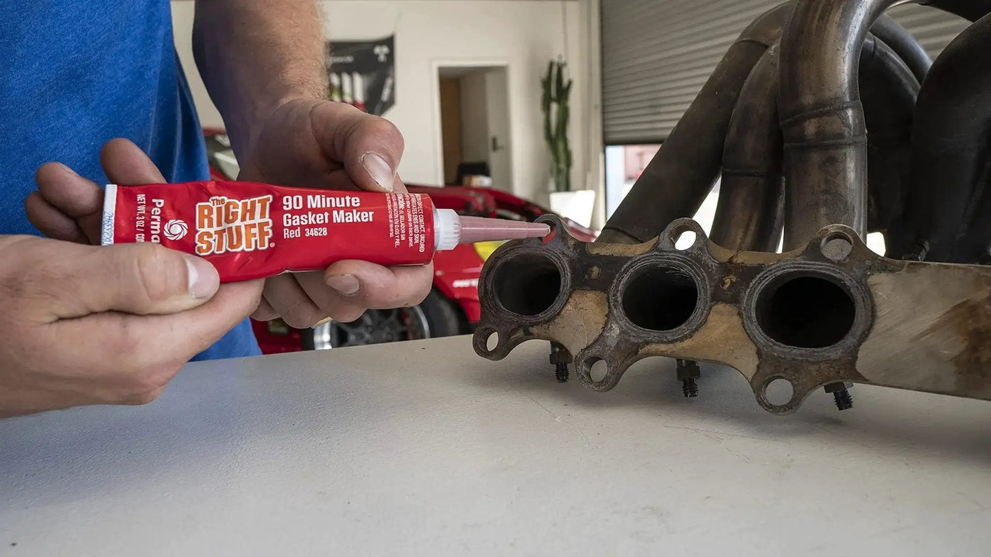 Person applying Right Stuff 90 Minute Red High Temperature Gasket Maker For Headers And Exhaust, 3 Oz Tube to exhaust manifold