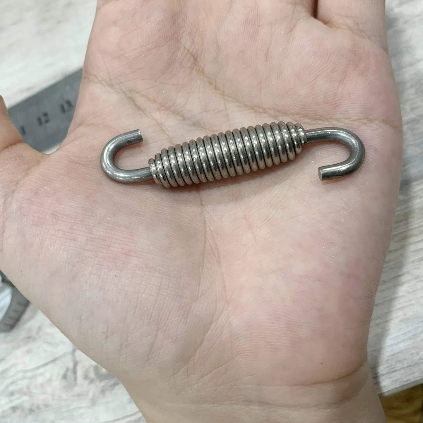 Hand holding Motorcycle Exhaust Spring Set 4 Pack Stainless Steel Swivel Hook Springs 58mm Long For Mufflers