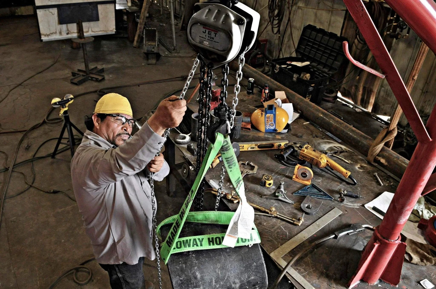 Worker using a 1 Ton Hand Chain Hoist For 10 Foot Lift Model S90 100 10 Gray With Industrial Rated Alloy Steel Hooks in a workshop.