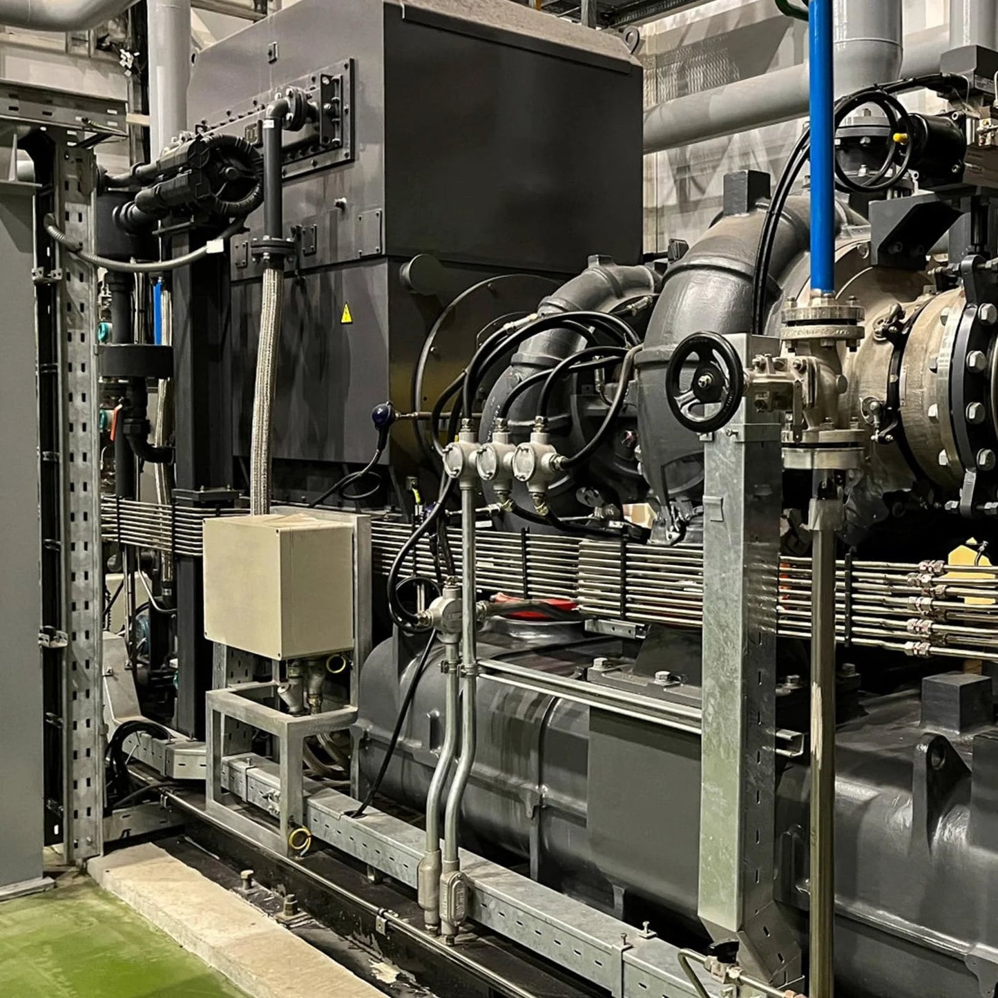 Industrial machinery setup with metal framework and various connected pipes, showcasing detailed engineering and construction.