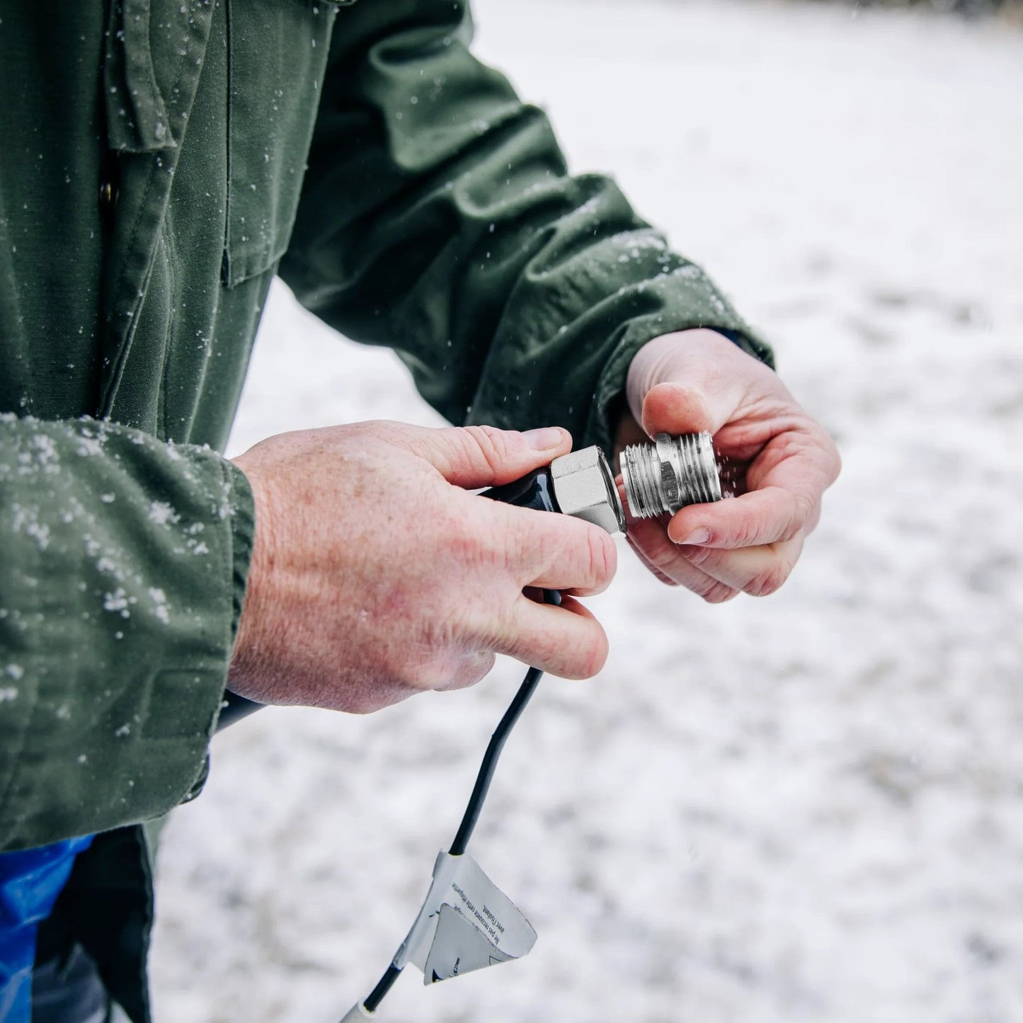 Person holding adapter of Heated RV Water Hose With Freeze Protection To Minus 20 Degrees Fahrenheit For All Weather Use Premium NSF 61 Drinking Water Hose Lead Free BPA Free Phthalate Free With Energy Saving Thermostat And Adapter For Connection To Either End Of Hose