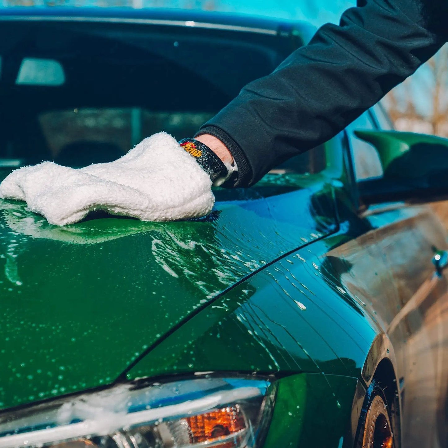 A person cleaning a green car hood with a microfiber cloth using Gold Class Car Wash Shampoo And Conditioner Delivers Pro Results In Foam Cannon Or Bucket Wash While Preserving Wax Protection And A Glossy Finish For All Paint Types 64 Oz Meguiar's.
