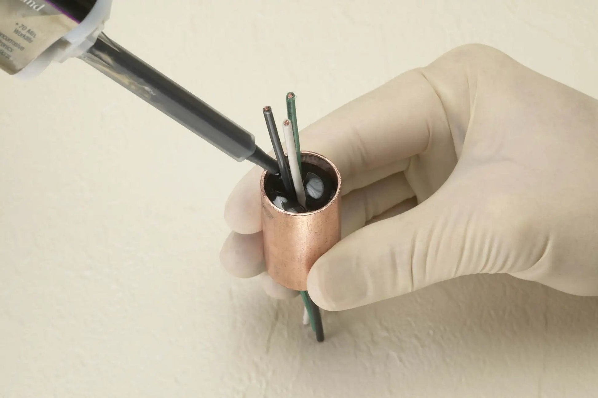 Applying 3M Scotch-Weld Clear Epoxy Adhesive DP100 Plus to wires in a copper fitting, showcasing reliable bonding application.