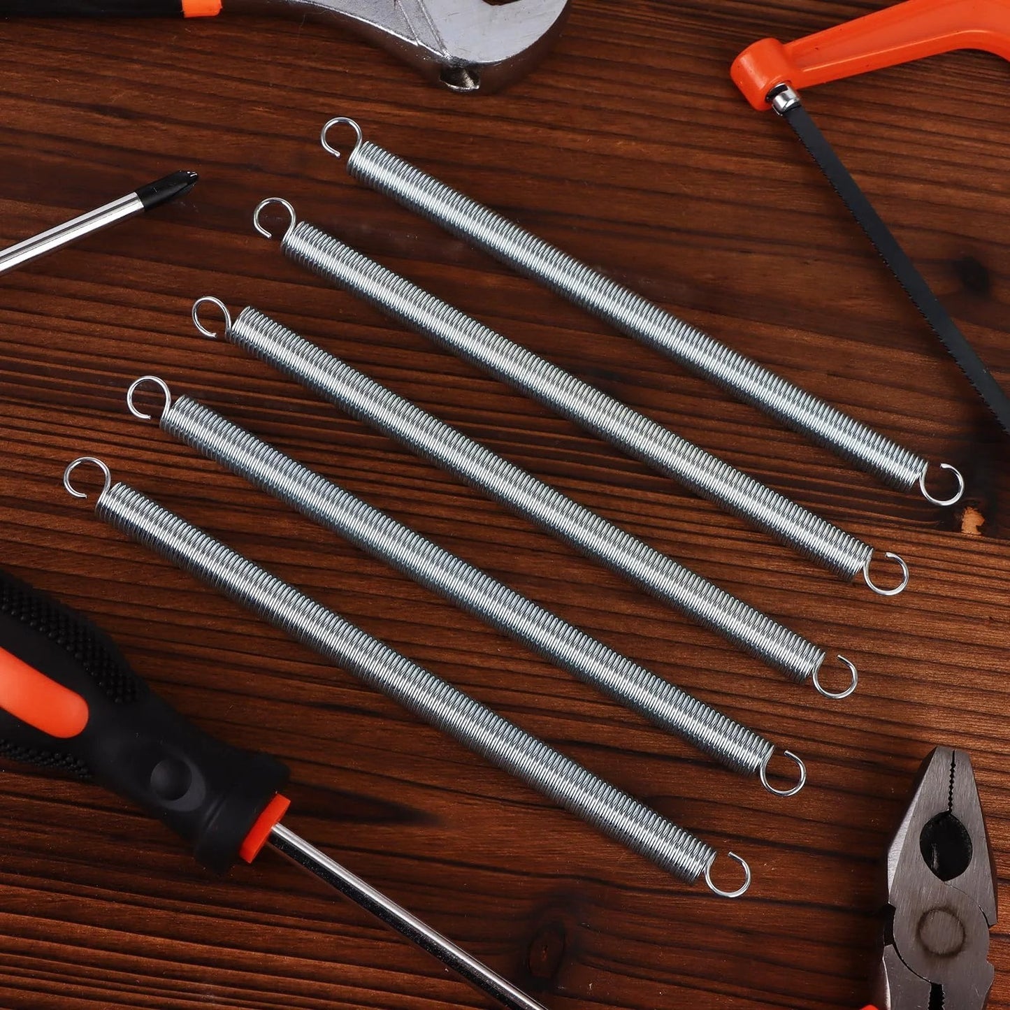 12 Piece Extension Spring Set For Home Repairs And DIY Projects Three Eighths By Six And A Half Inch Zinc Plated With Dual Hook Ends And A Slim 0.047 Inch Wire Great For Machinery Construction And Industrial Use shown with tools
