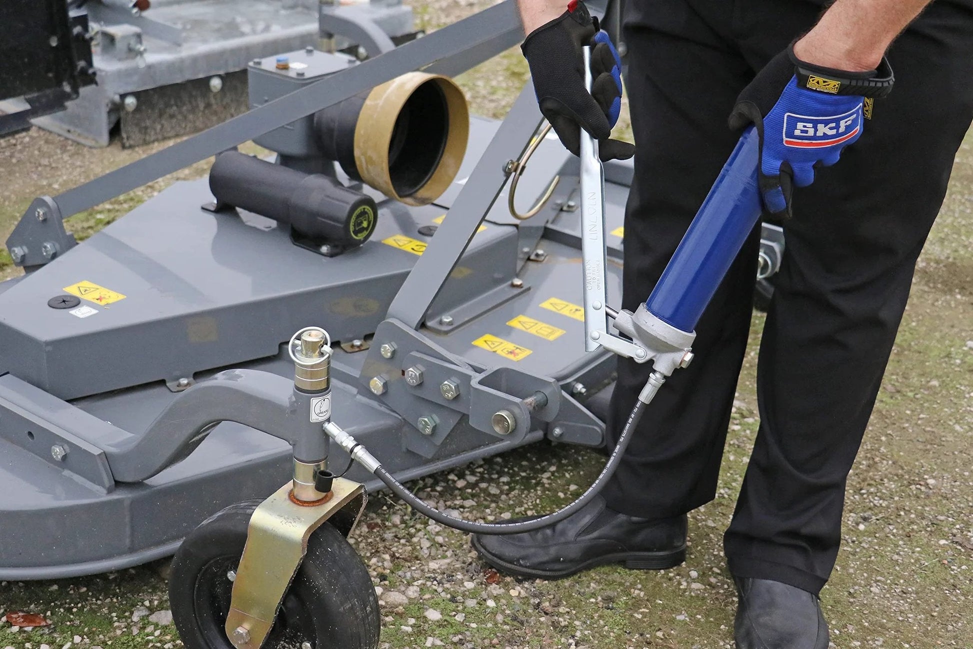 Heavy Duty Lever Action Grease Gun With 18 Inch Whip Hose And Coupler, Jam Proof Toggle, Cast Pump Head, being used on machinery